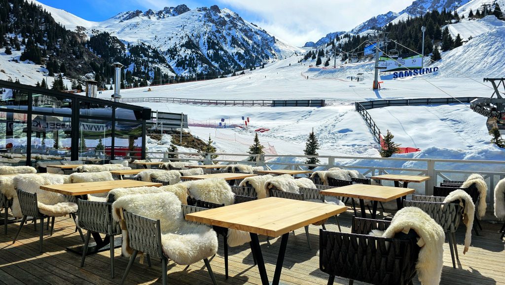 Outdoor mountain café at Shymbulak Ski Resort in Kazakhstan, with snowy slopes in the background.