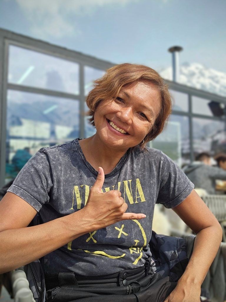 Me smiling with the snowy mountain backdrop at Shymbulak Ski Resort in Kazakhstan.