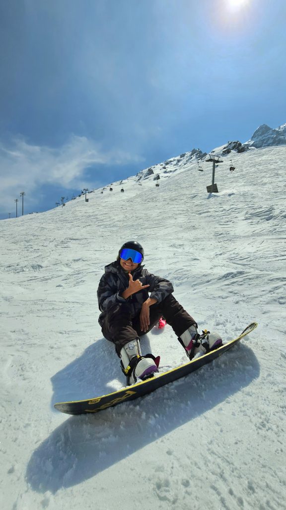 Me snowboarding down the snowy slopes at Shymbulak Ski Resort in Kazakhstan.