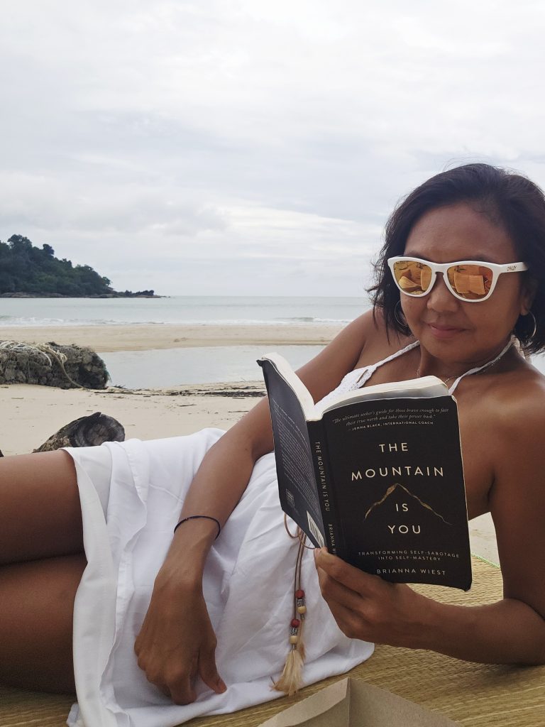 Shannim reading on the private beach at Berjaya Langkawi with a picnic spread beside her.