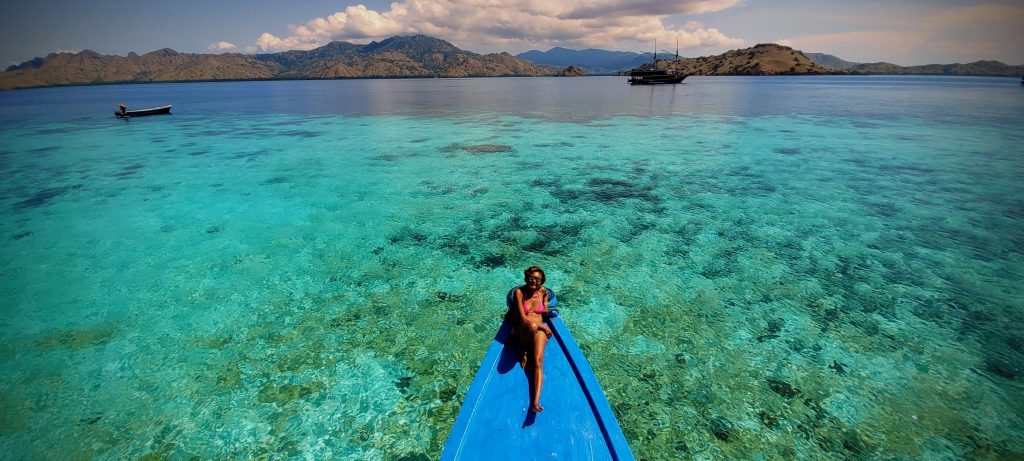 Traveller on a wooden boat in clear waters of Komodo National Park