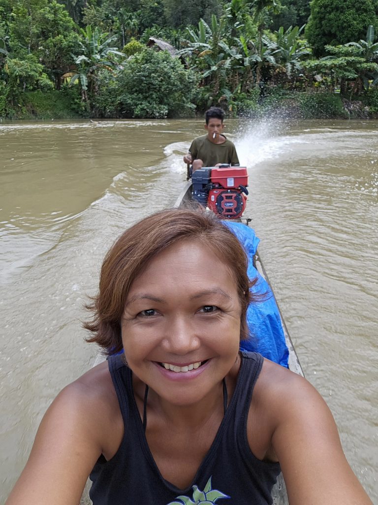 Shannim, a travel writer, on a wooden canoe heading up the Siberut River to visit the Mentawai Tribe in Indonesia.