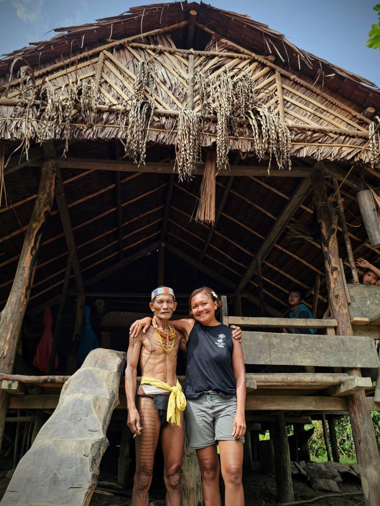 Shannim standing with the Mentawai shaman Aman Sergi inside the uma in Siberut, Indonesia.