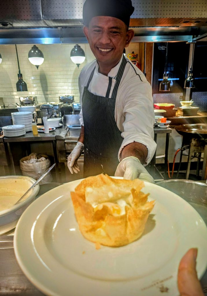 Chef handing the freshly made apam telur