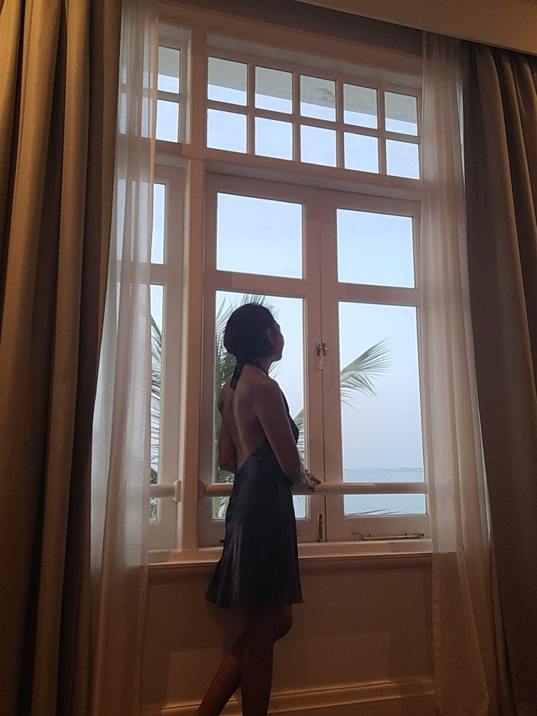 Travel writer Shannim standing by the window in the Deluxe Suite at Eastern & Oriental Hotel Penang with sea views