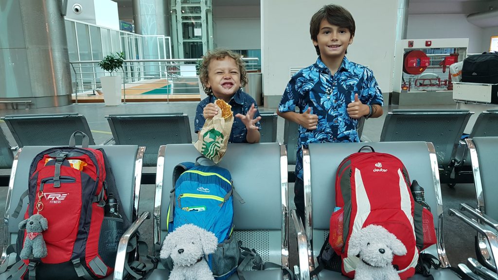 Two boys standing at the airport with their rucksacks while travelling light as a family