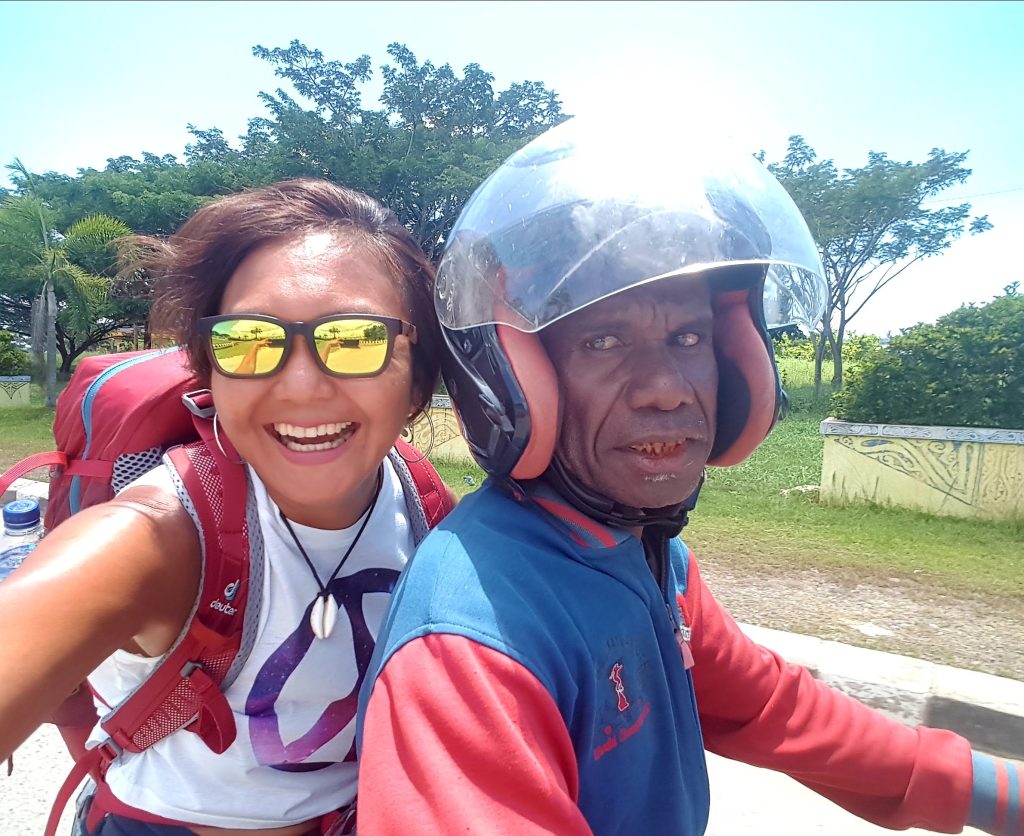 The writer with a rucksack travelling light on the back of a motorbike in Papua