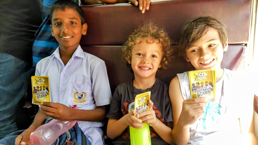 Two boys travelling light on a local train in Sri Lanka sitting with local passengers