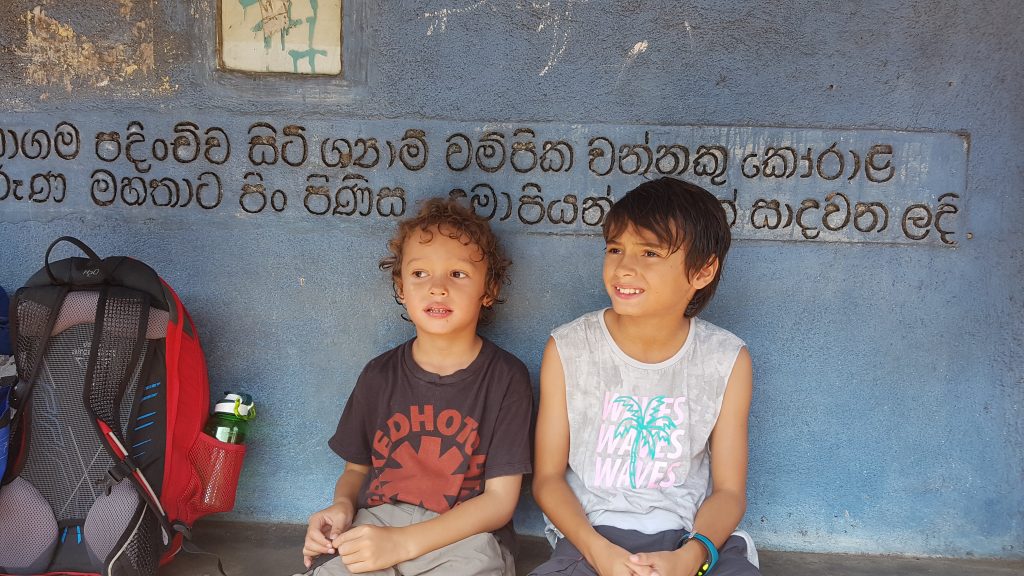 Children travelling light while waiting at a bus stop in Sri Lanka