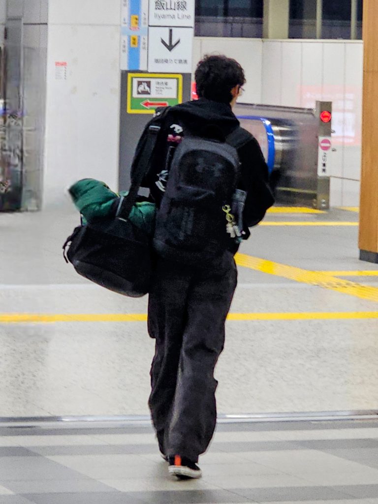 Teenager travelling light while leaving a train station in Japan with his backpack