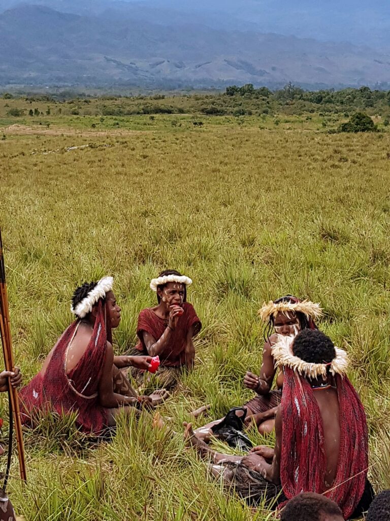 Dani women sitting on the grass before a performance at the Baliem Valley Festival